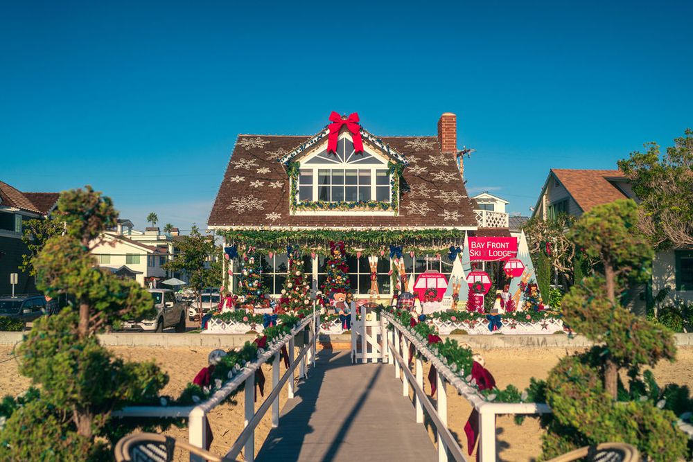 A panoramic view of a busy boardwalk with shops and restaurants along a beachfront on a sunny summer day.