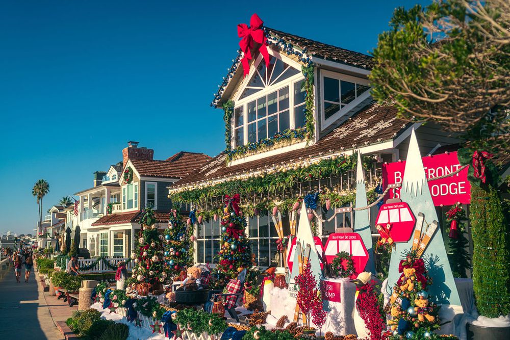 Coastal homes decorated with festive red bows and holiday greenery along a beachfront neighborhood during Christmas season.