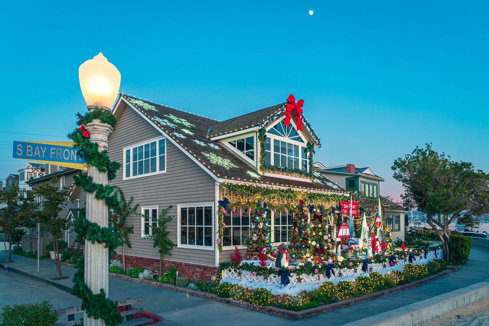Coastal restaurant exterior with blue sky and palm trees featuring white siding and outdoor dining area.