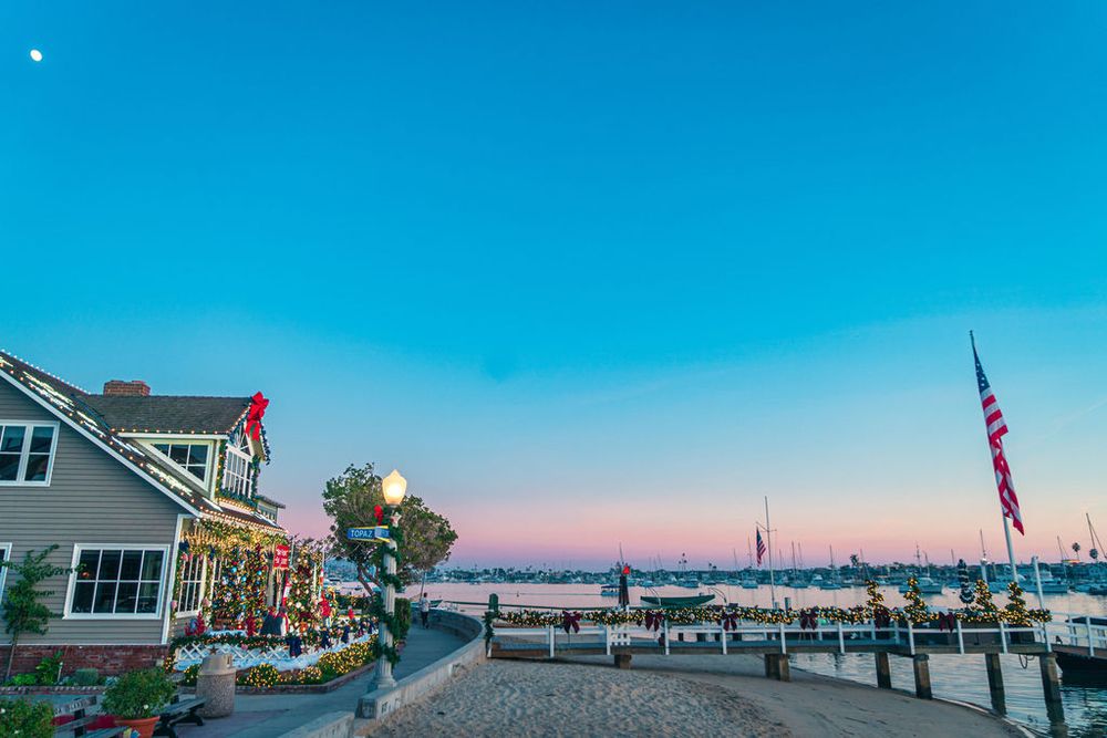 Panoramic view of a seaside marina at dusk with boats and piers silhouetted against a blue twilight sky.
