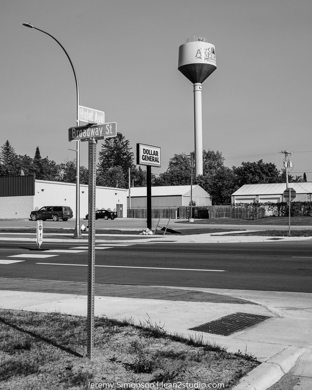 Black and white street scene showing a water tower and intersection with street signs in a suburban area.