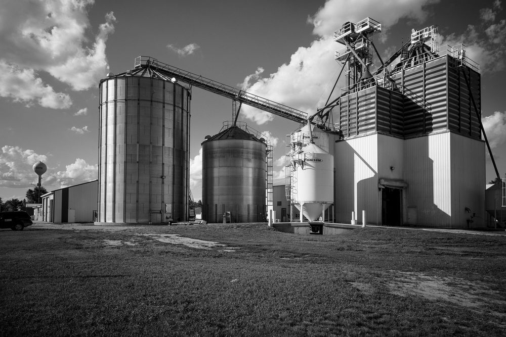 A series of black and white photographs showing grain elevators and agricultural storage facilities against cloudy skies.