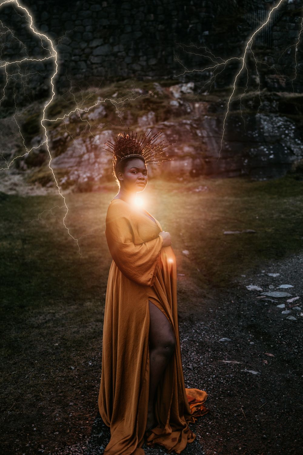 A cloaked figure stands in darkness holding a glowing light while lightning strikes dramatically in the stormy sky above.