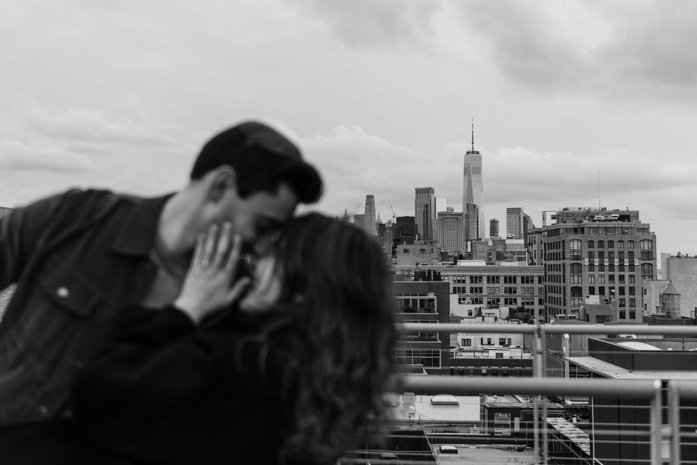 Black and white photo of intimate moment on NYC rooftop with skyscrapers in background.