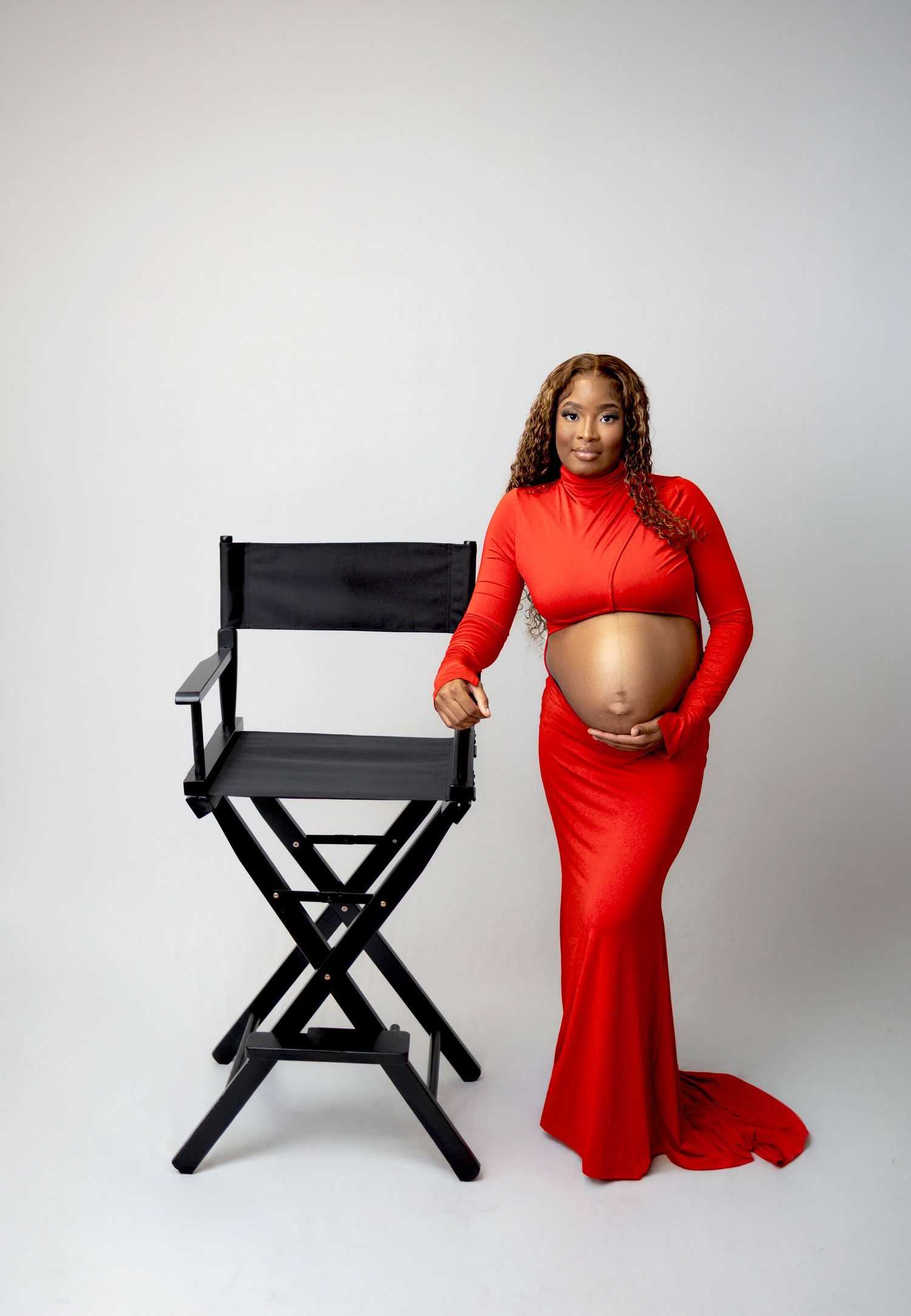 A series of maternity portraits showing a woman in a flowing blue dress against a moody clouded backdrop.