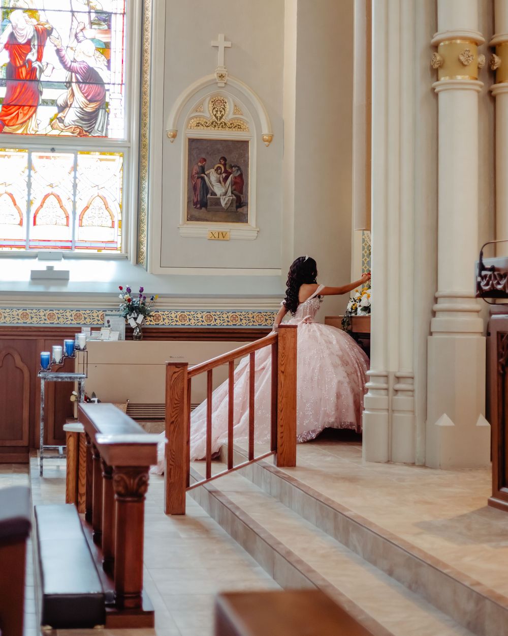 A flowing pink ball gown dress moves through church pews beside stained glass windows and classical architecture.