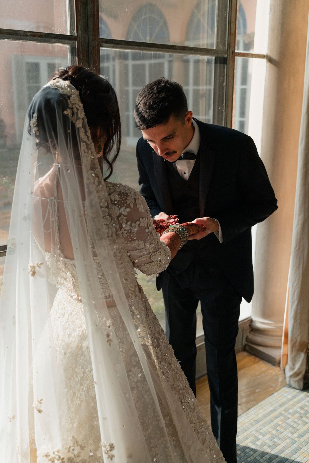 A groom searches for his name in brides henna at Cuneo Mansion.