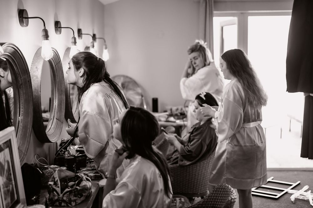 Black and white image of people getting ready at mirrors and vanity stations.