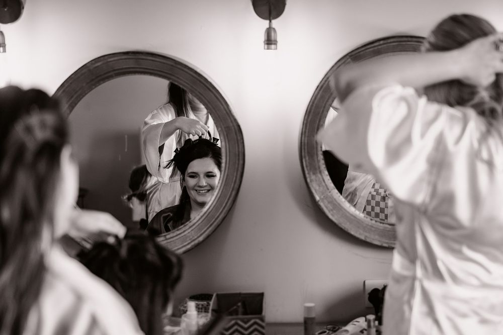 Black and white reflection in circular mirror showing wedding preparation moment.