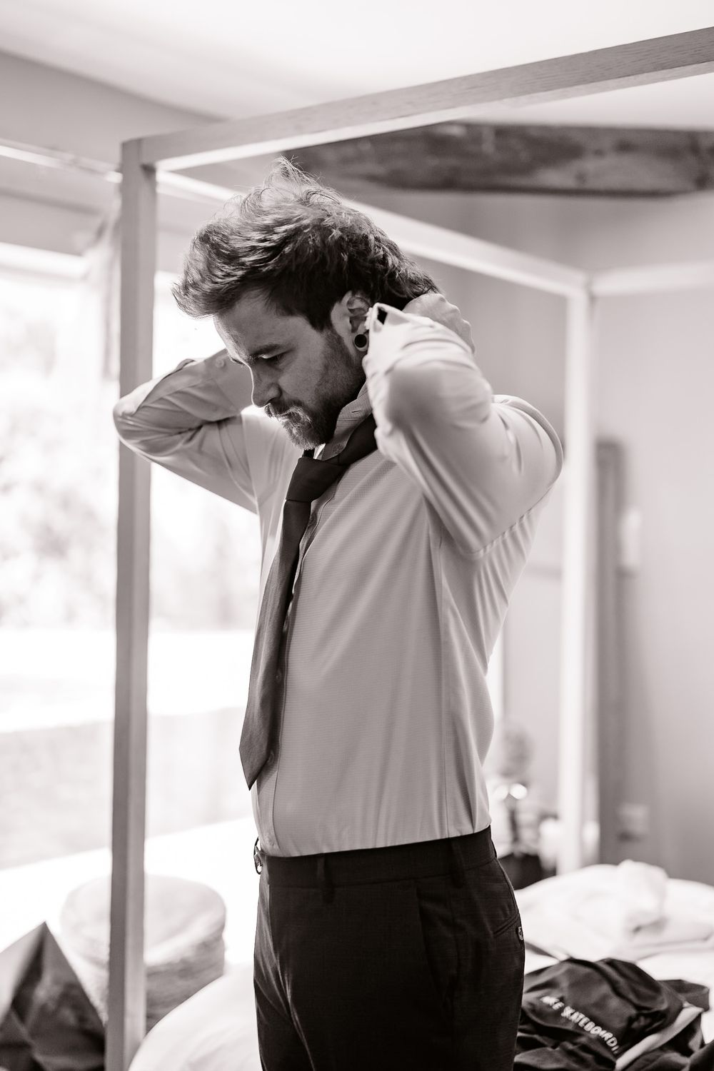 Black and white portrait of a person getting dressed in formal attire.