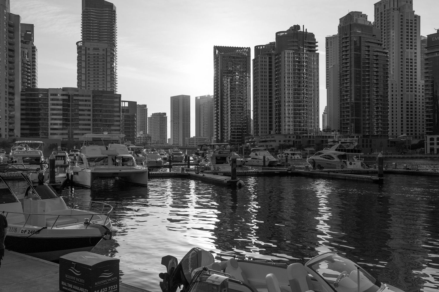Panoramic black and white cityscape view of Dubai Marina with modern skyscrapers reflecting in calm waters.