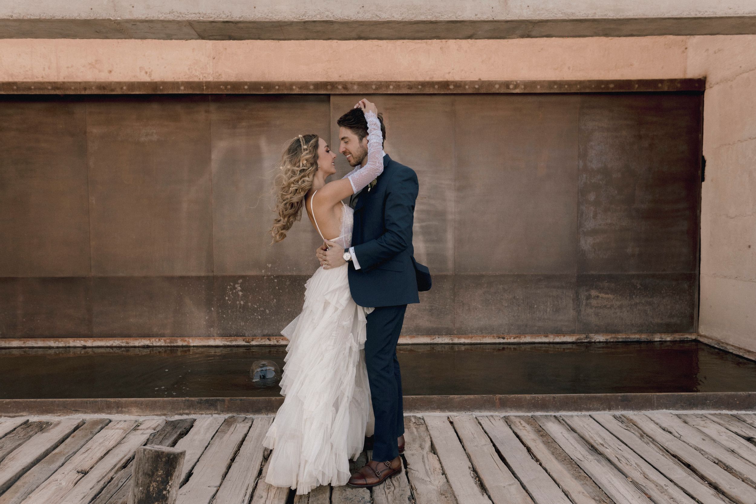 A couple shares their first dance at an outdoor wedding reception as guests watch from the background.
