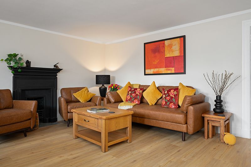 Panoramic view of a modern living room with brown leather sofa, wooden coffee table and orange wall art decor.