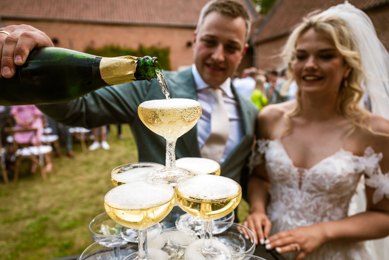 Bruidspaar schenkt champagne tijdens huwelijksreceptie, een feestelijk en spontaan moment vol emotie vastgelegd door Bart Boodts.