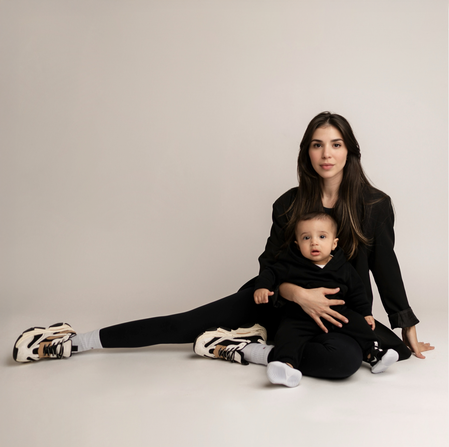 Minimalist studio photography session in black outfits against white backdrop.