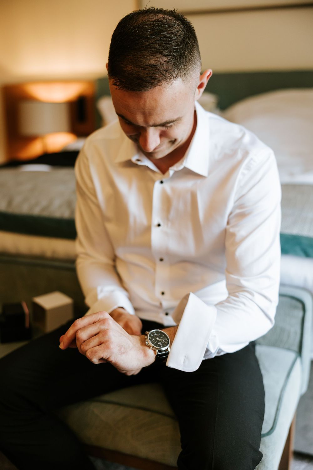 Close-up view of someone in a crisp white dress shirt and black pants adjusting their sleeves. Farnham estate