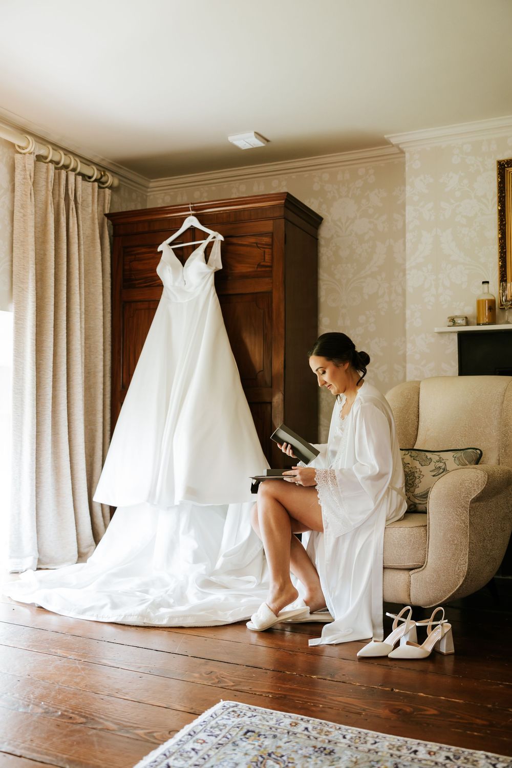 A white wedding gown and shoes arranged in a room with hardwood floors and natural lighting. Farnham estate