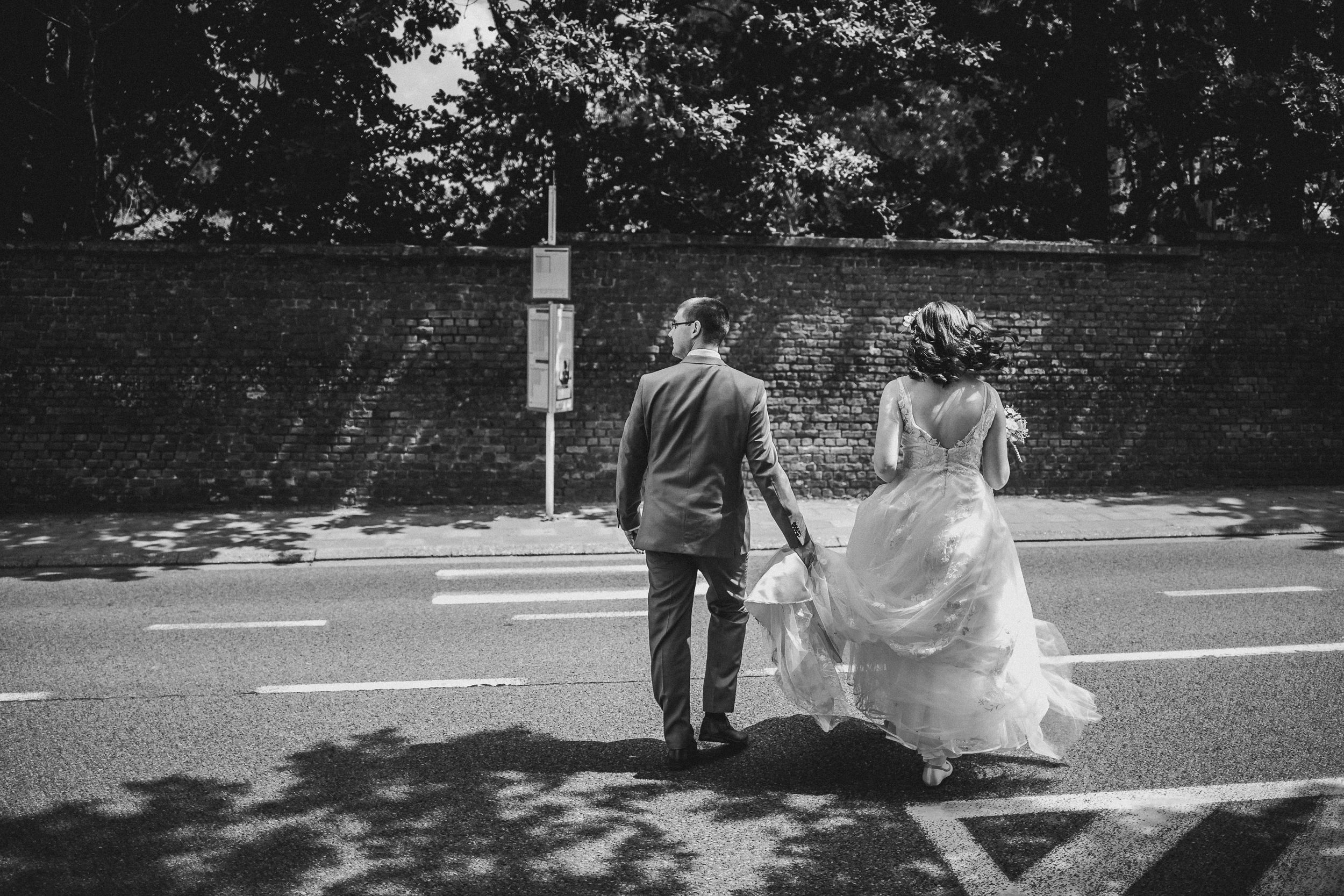 Black and white photo of couple walking together on a sunlit path.