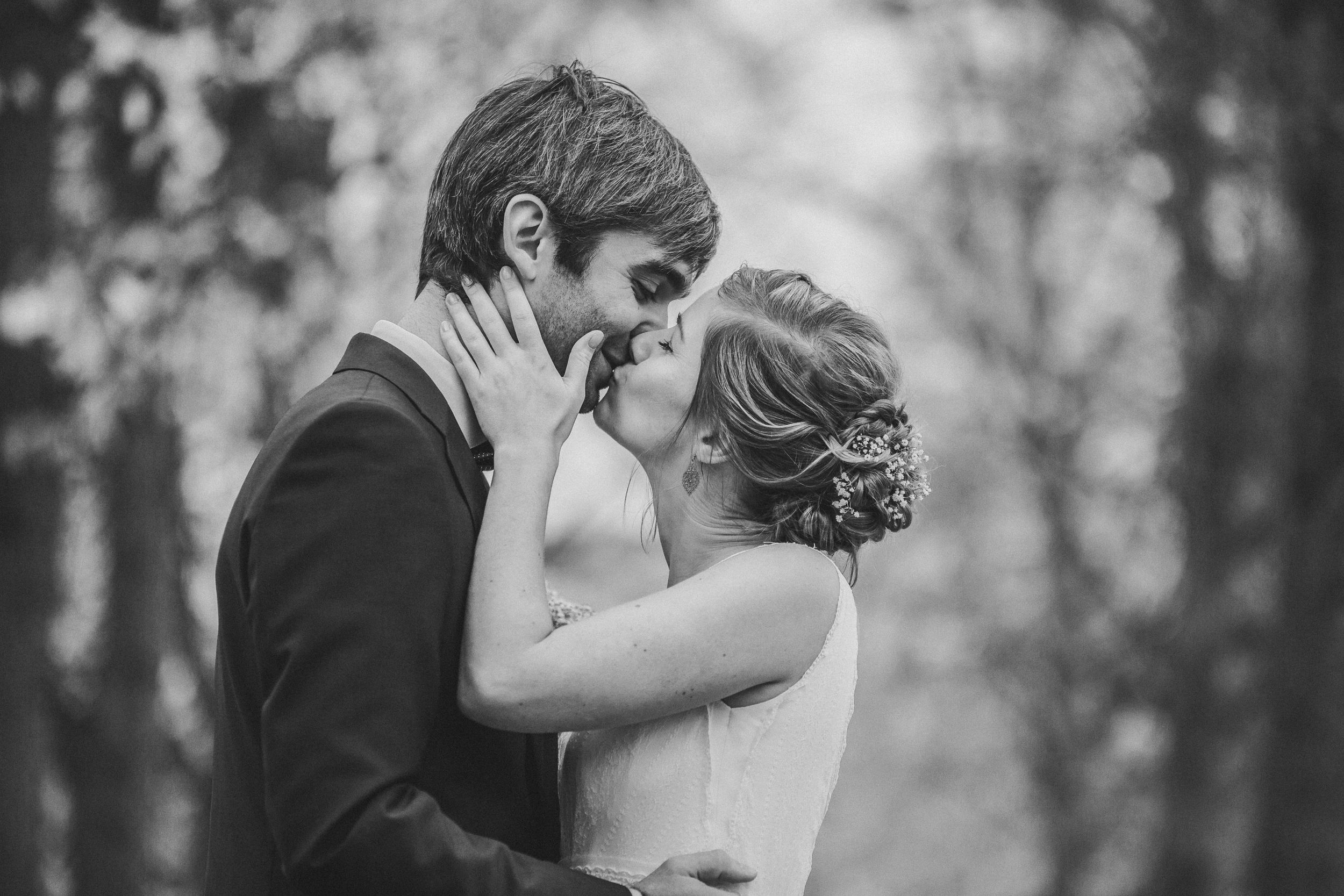 Black and white wedding portraits capturing candid romantic moments in a natural setting.
