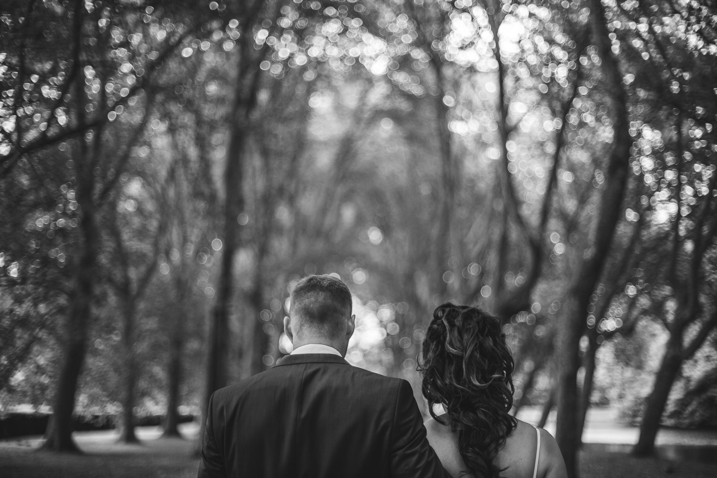 Black and white wedding photography in a moody forest setting with dramatic lighting.