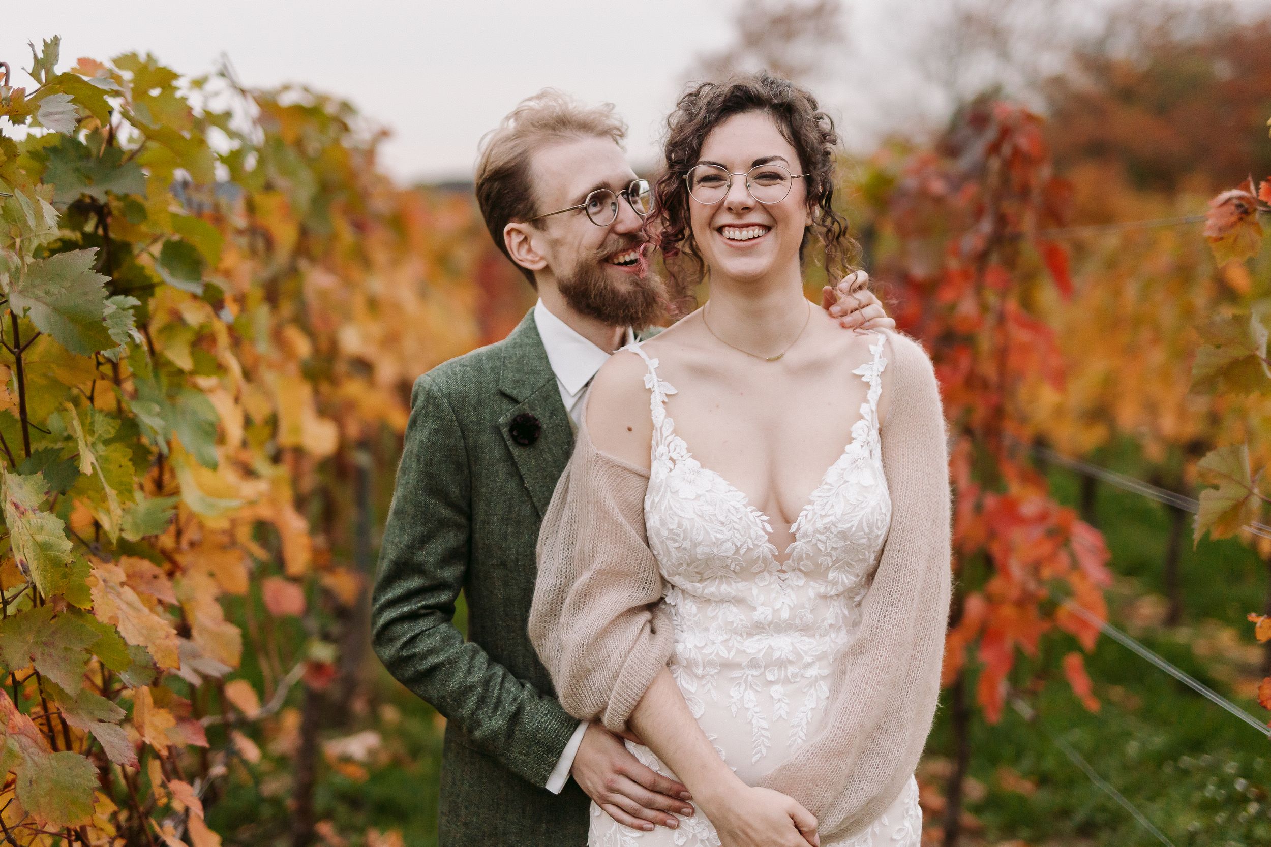 A couple shares romantic moments among vibrant autumn vineyard foliage in a wedding photoshoot.