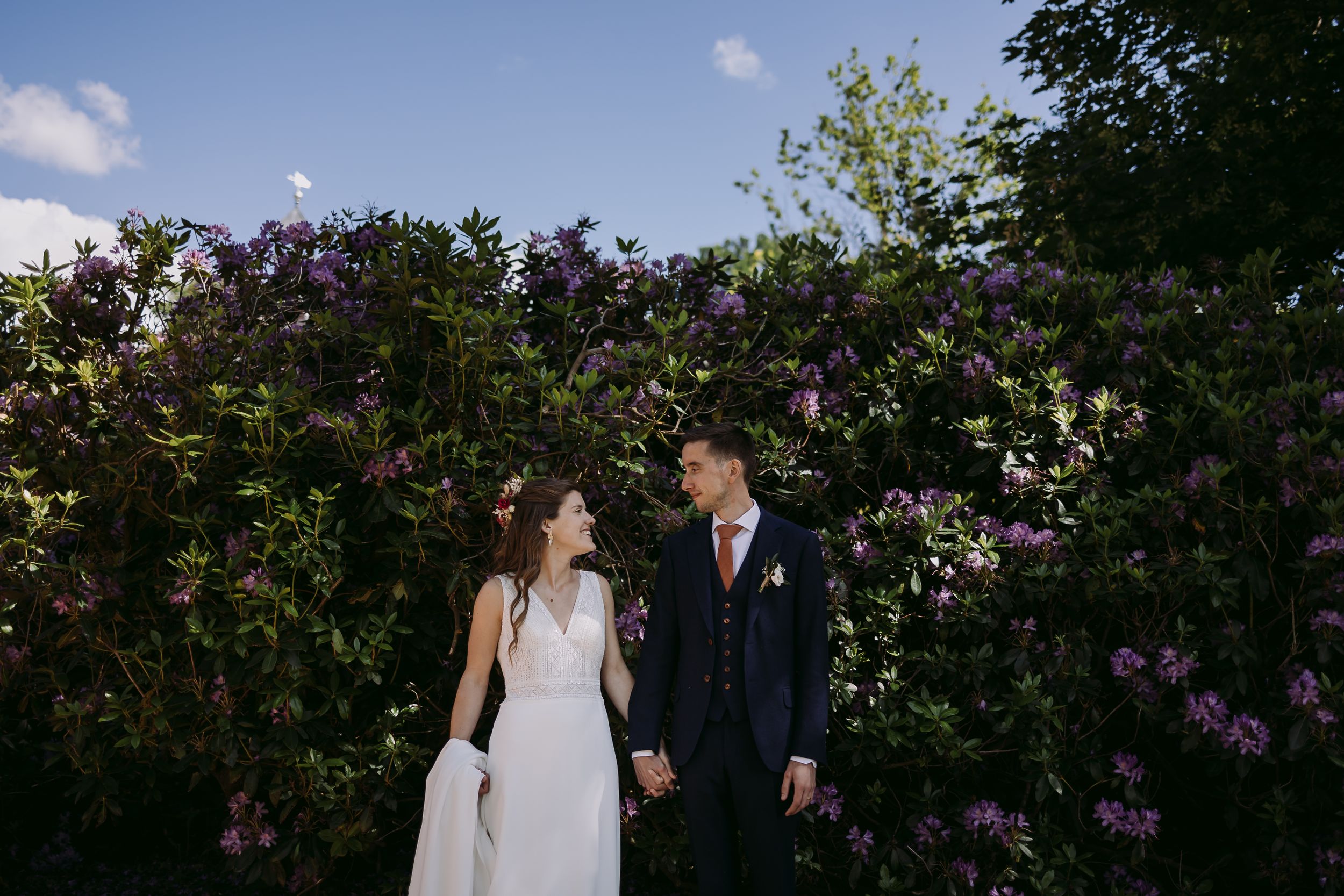 Couple posing together against a backdrop of blooming lilac flowers.
