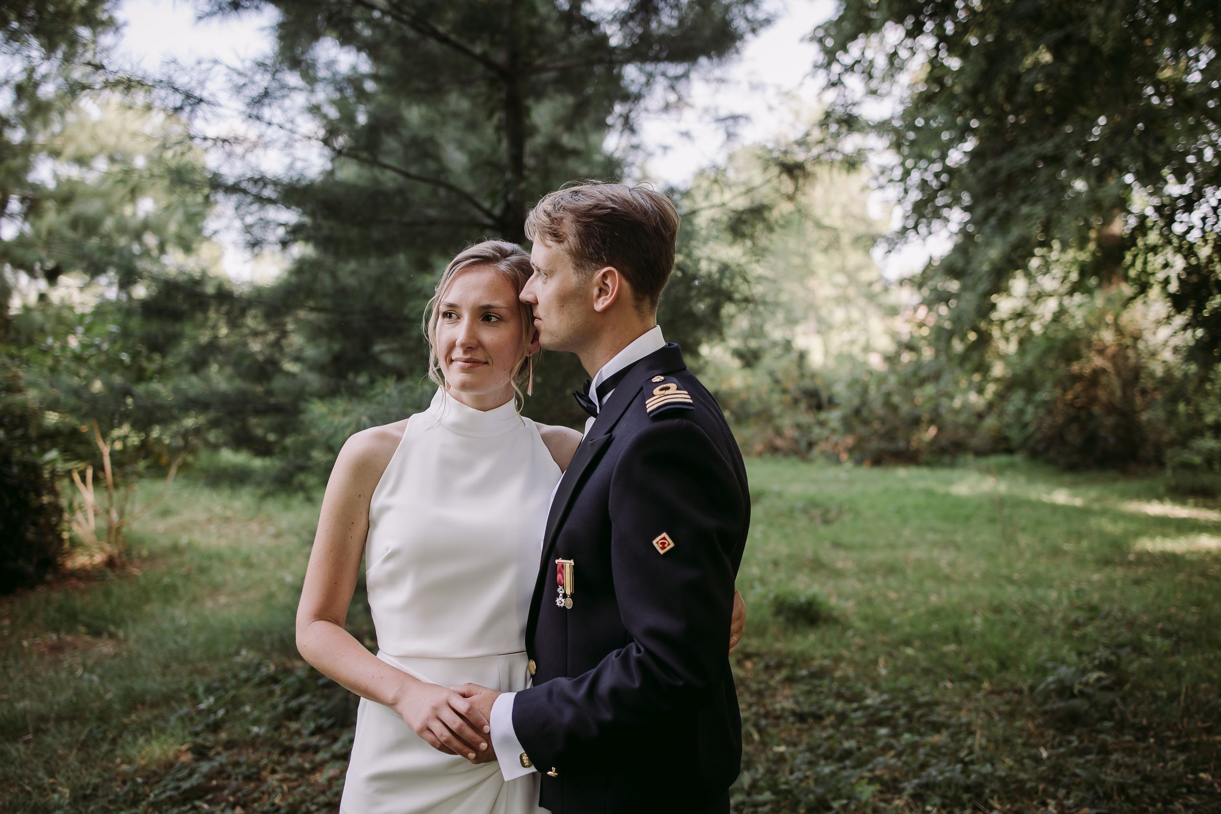 Elegant wedding photos taken in a wooded setting with pine trees and dappled sunlight.