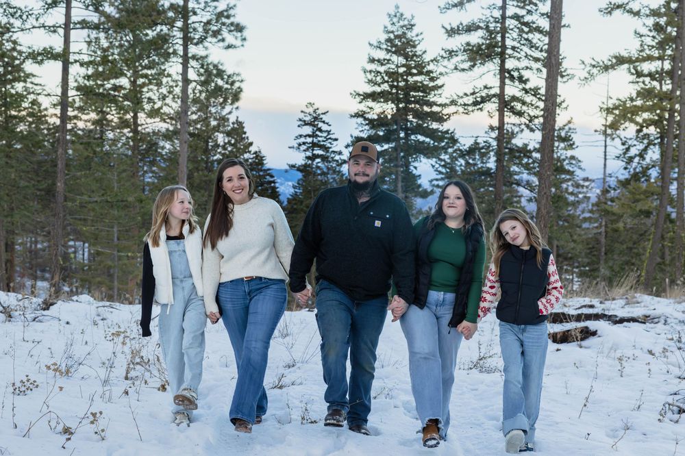 Family walking together through a snowy forest path during winter.
