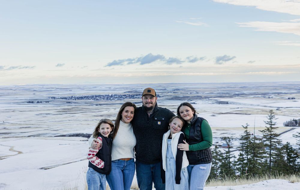 Winter family photos with snow-covered mountains and evergreen trees in background.