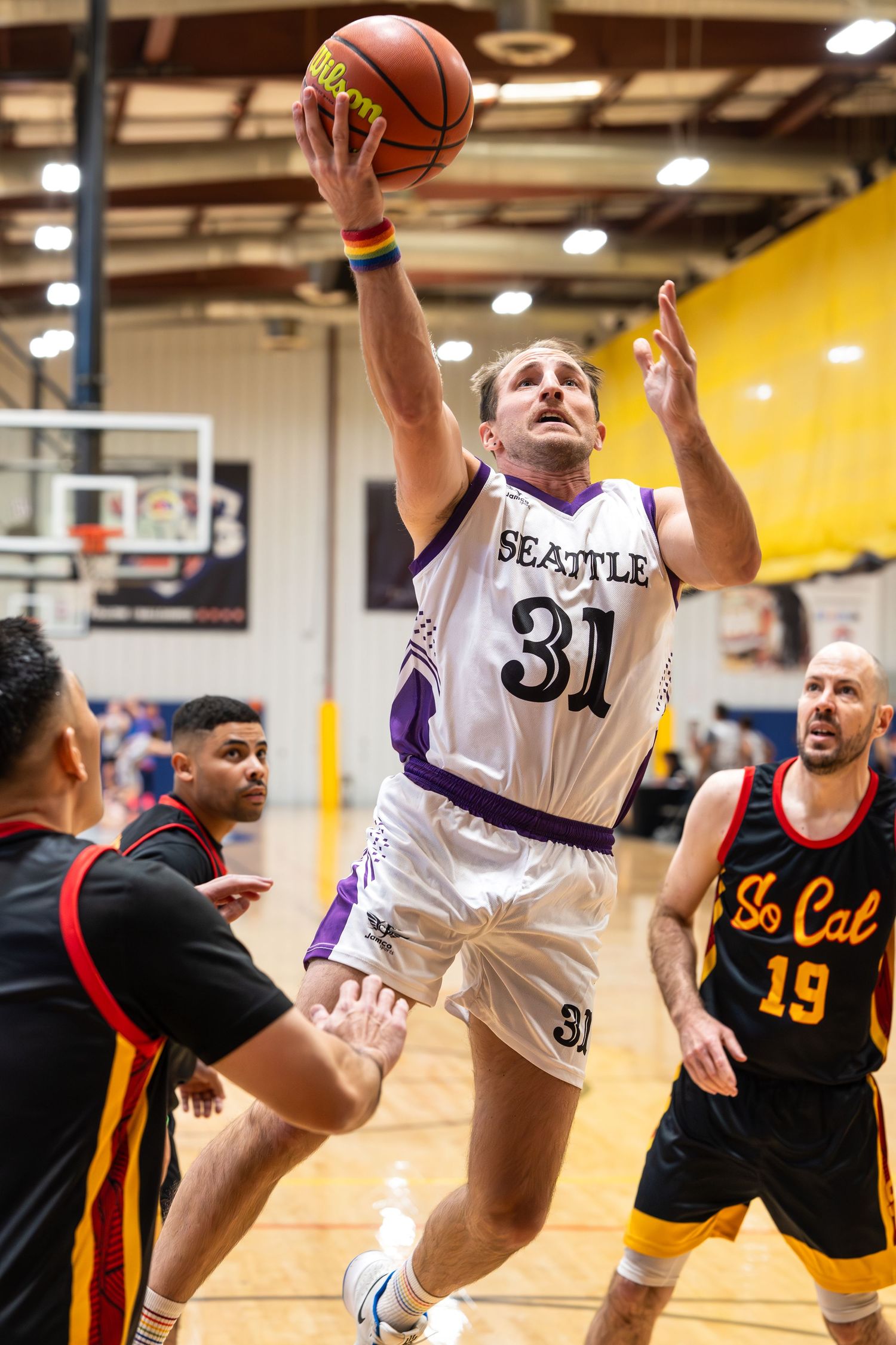 A basketball player surrounded by two defensive players makes a layup at a basketball tournament at Sin City Classic