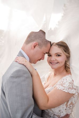 An intimate wedding portrait showing a tender moment between the newlyweds against a light background.