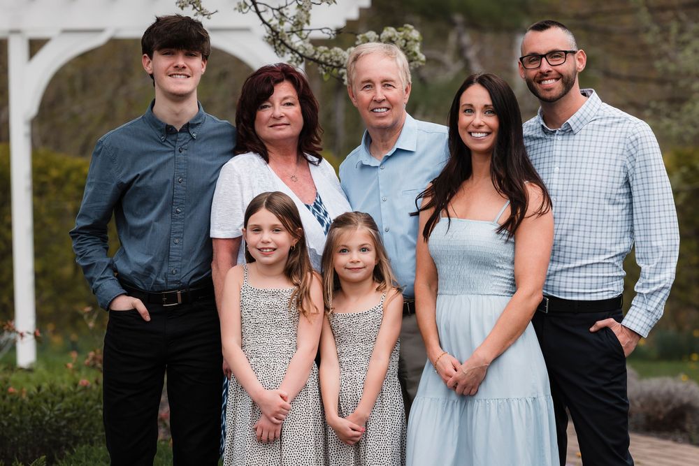 Multi-generation family portrait outside with adults and young children wearing coordinated dressy casual attire.