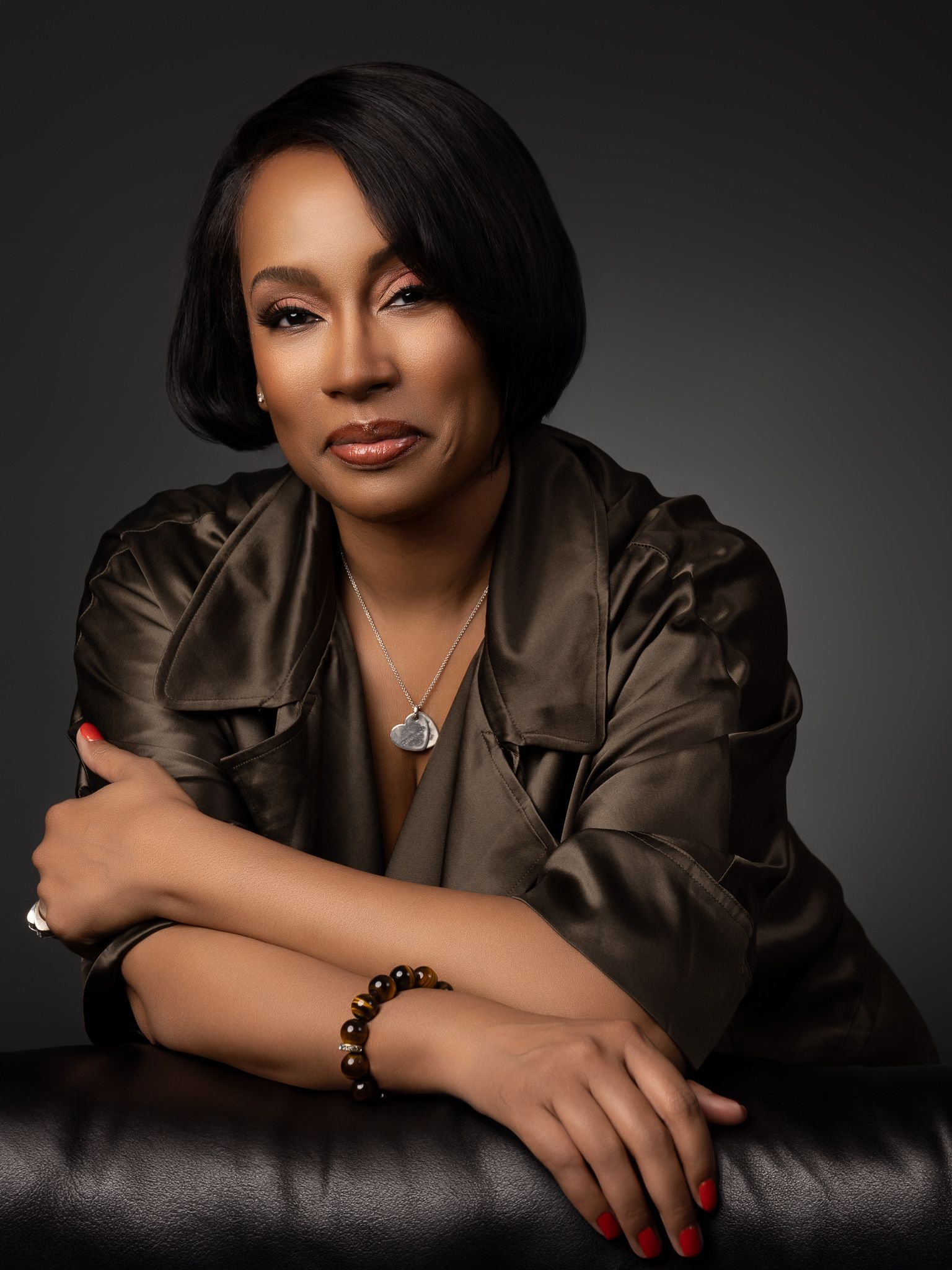 Professional studio portraits with dramatic lighting and brown satin outfit against dark background.