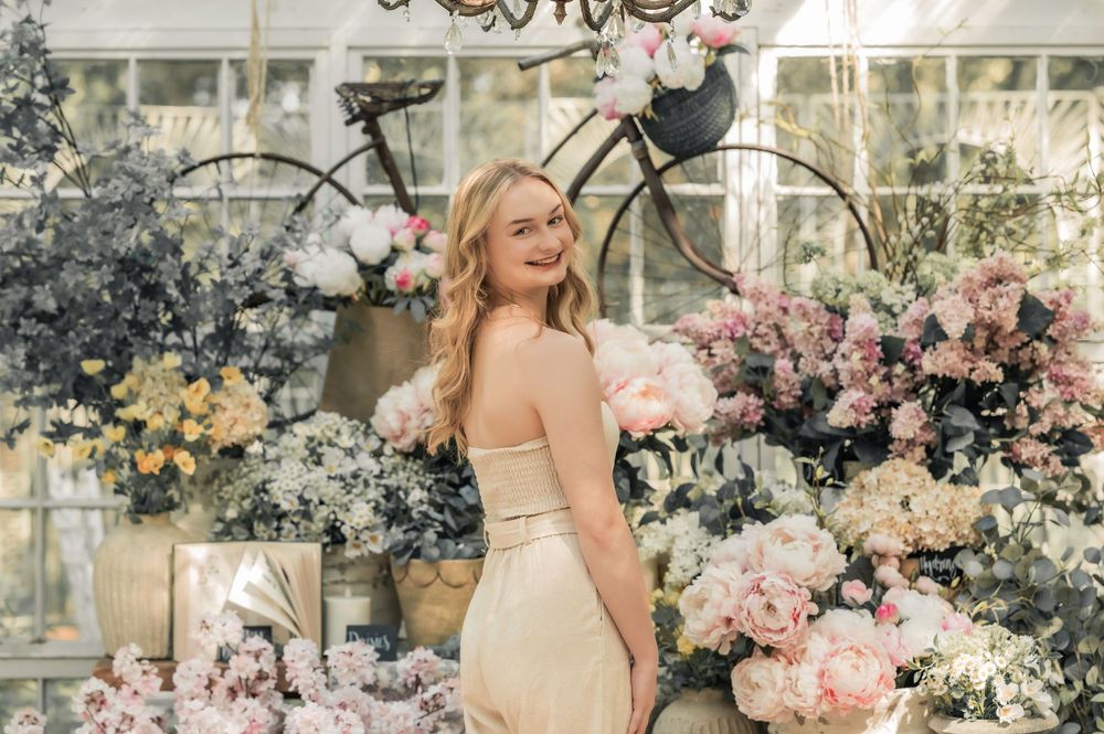A vintage bicycle decorated with pastel flowers stands in a romantic garden setting with soft pink and yellow blooms.