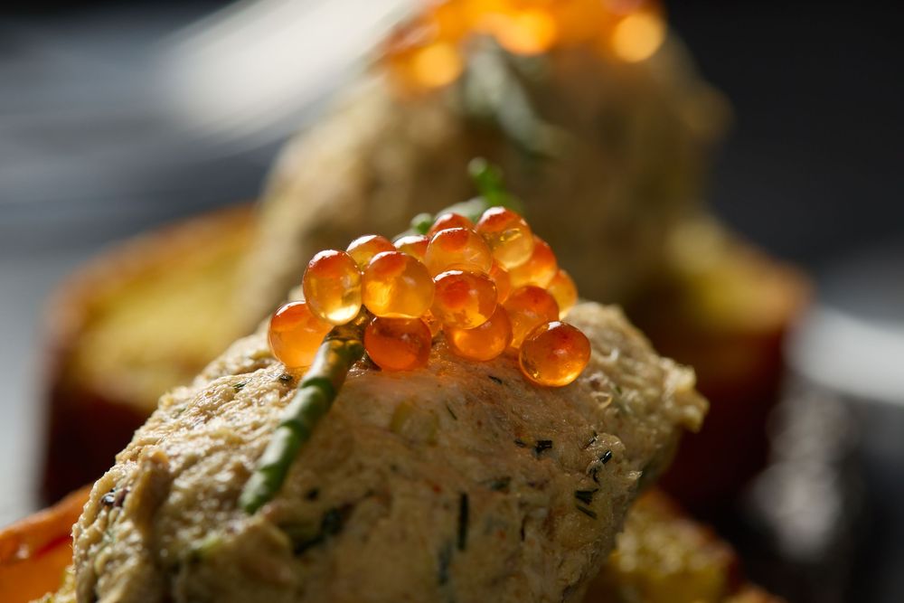 Close-up of salmon roe garnishing a delicate appetizer dish.