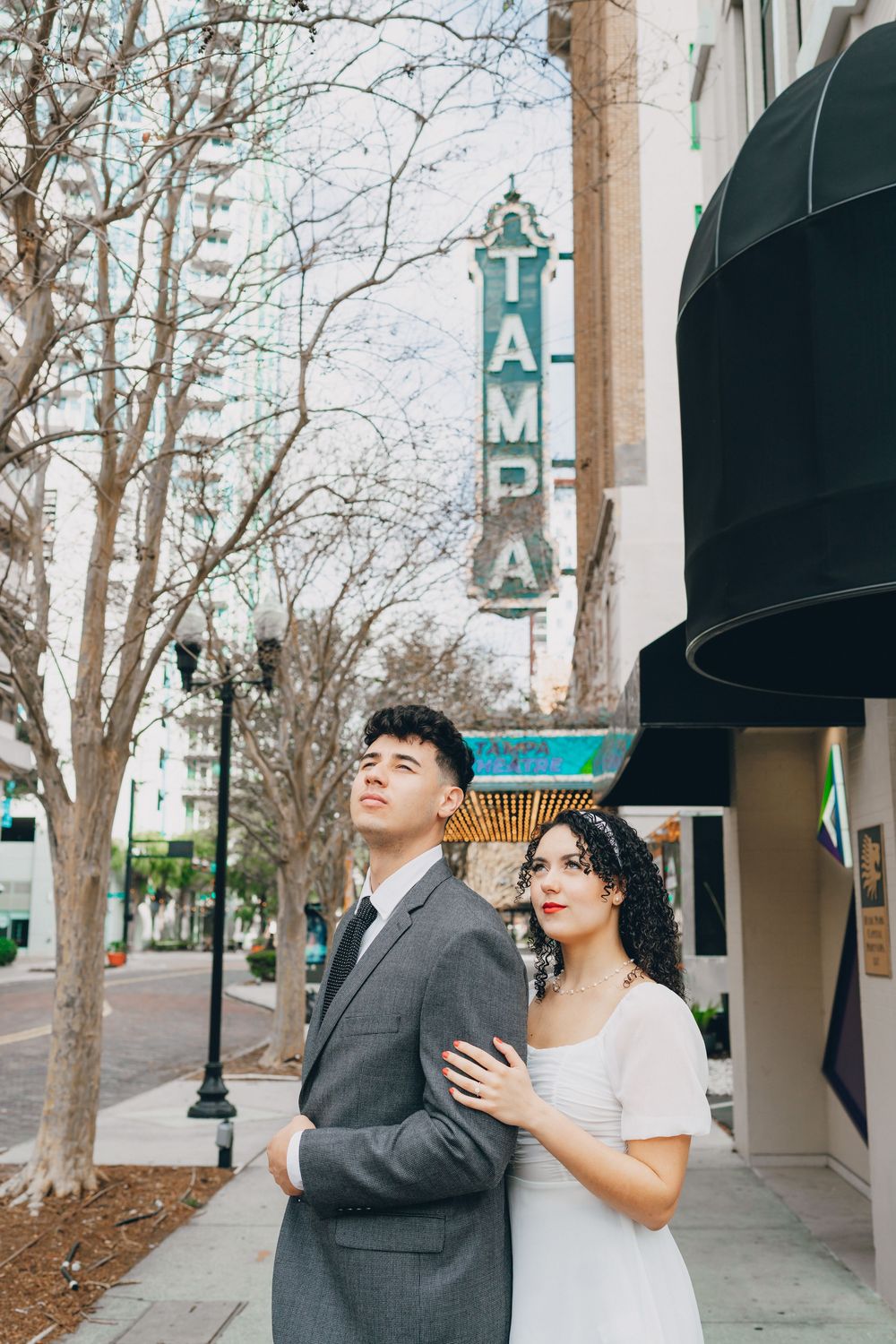 A romantic couple poses together outside the historic Tampa Theatre with its vintage vertical sign.