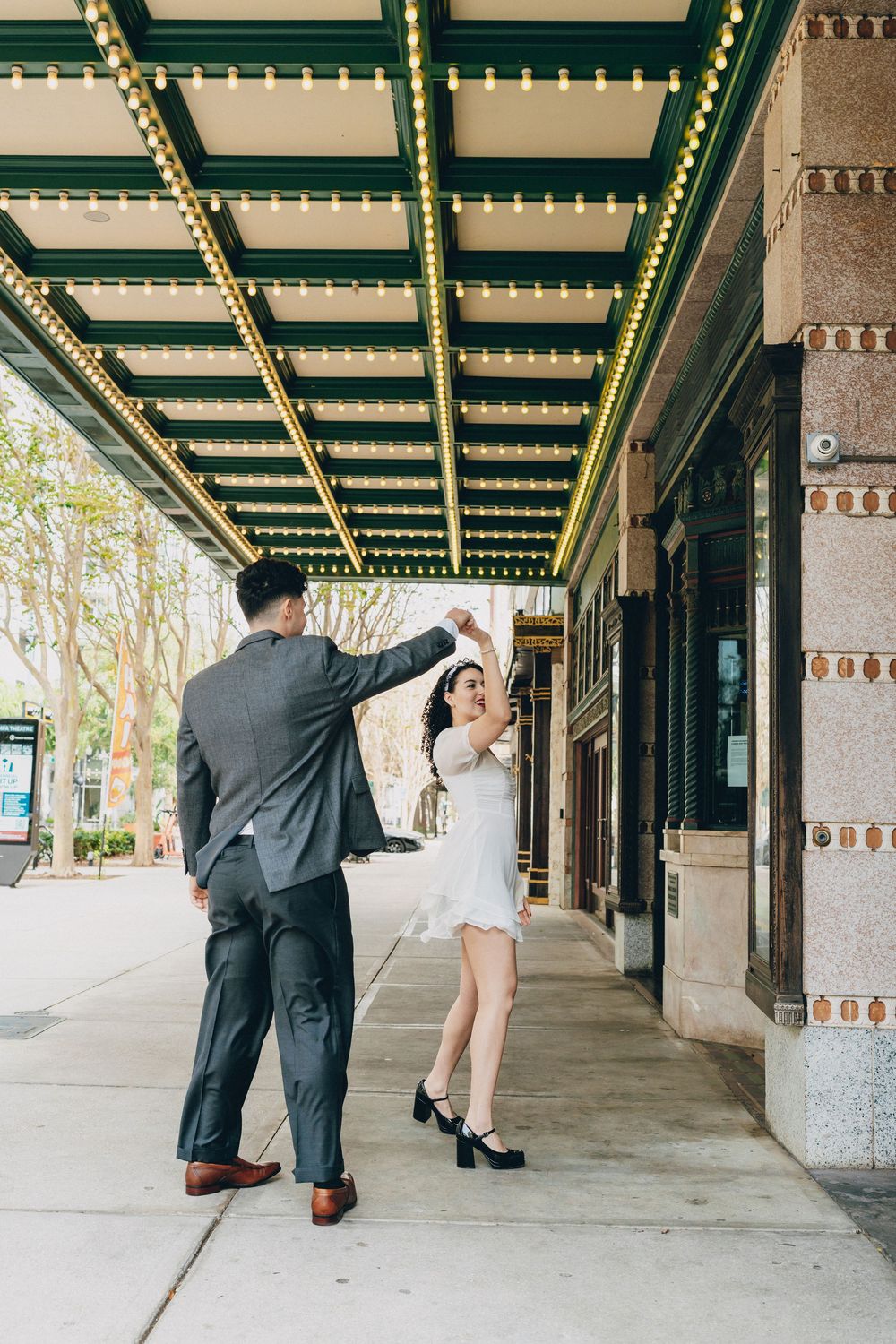 A couple dancing and twirling beneath a decorative ceiling with string lights.