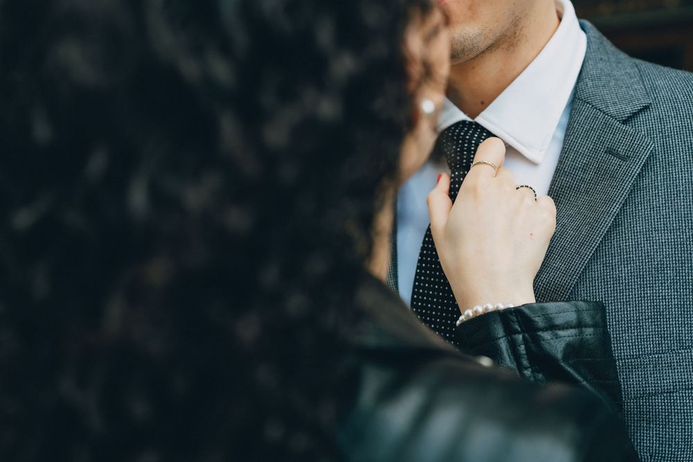 Close-up detail of a gray suit jacket with polka dot tie being adjusted.