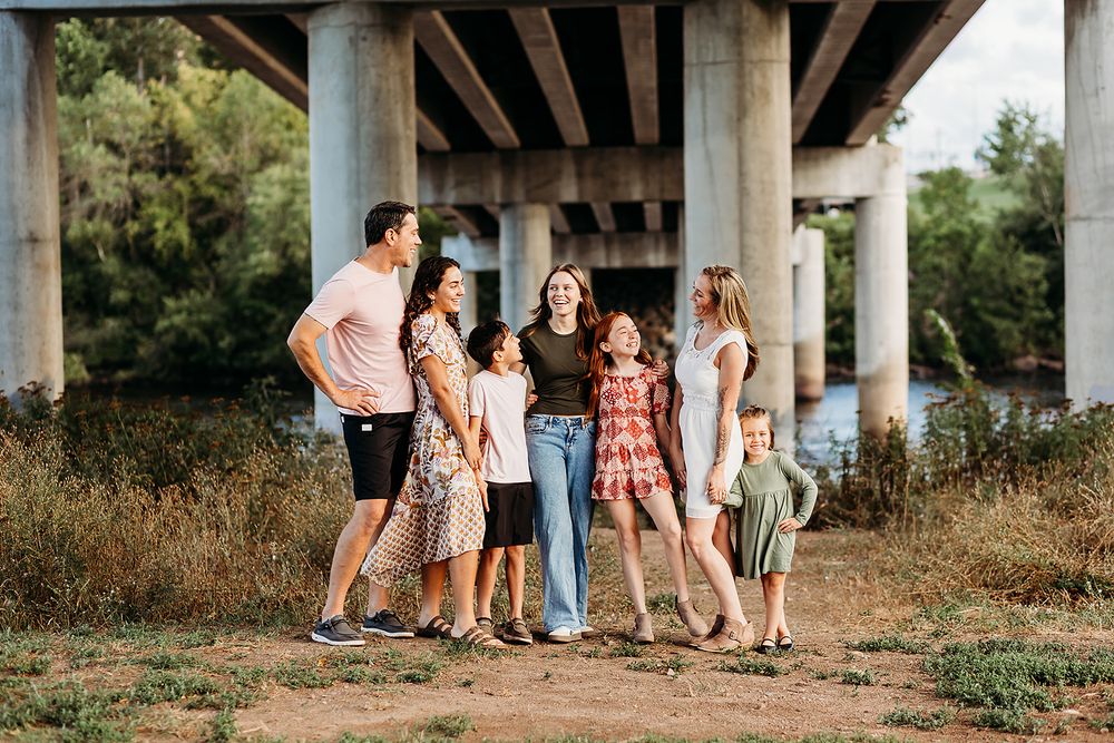 A group of people standing together under a concrete bridge during a golden hour photoshoot.