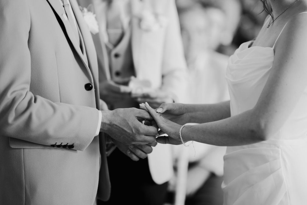 Bride and groom exchanging rings during wedding ceremony, close-up black and white photograph.