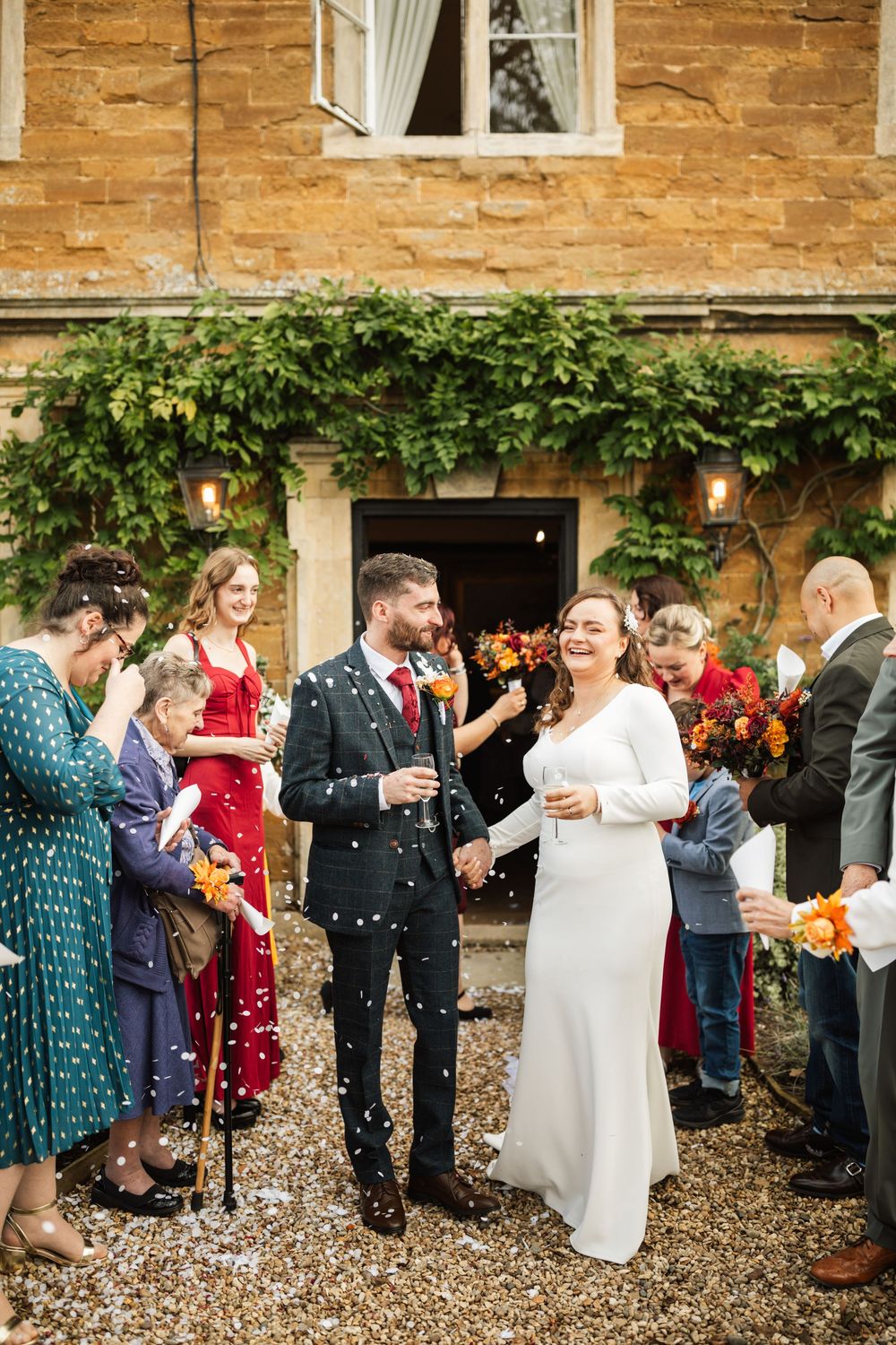 Wedding celebration with confetti on a stone building patio with climbing vines and autumn decor.