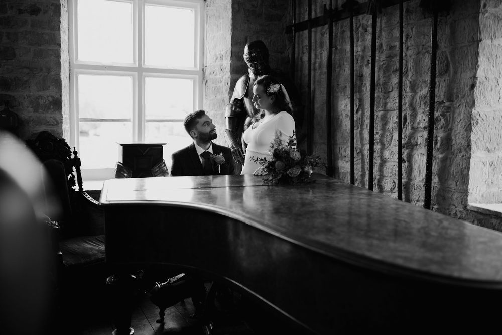 Three people gathered around a large conference table in a room with a window in black and white photography.