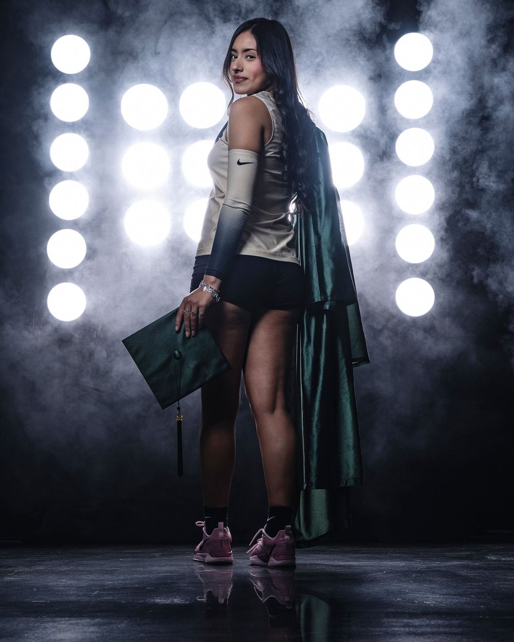 Athletic figure poses dramatically in sporty attire and long coat against illuminated background with fog effects.