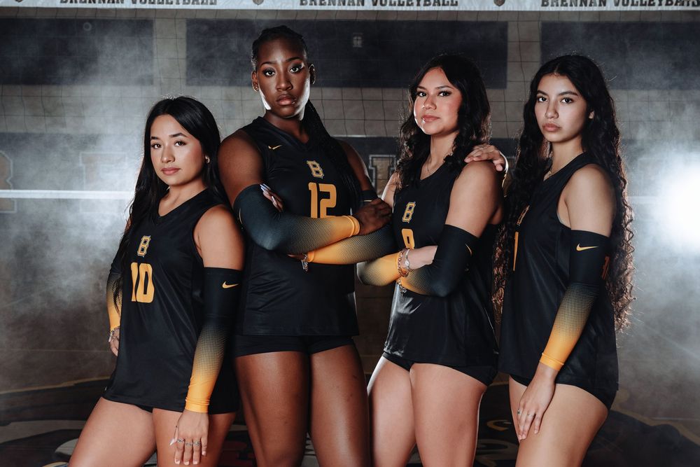 A sporty team photo of four athletes in matching black and yellow uniforms posing together against a dark background.