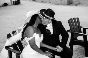 A newly married couple shares an intimate moment on an Adirondack chair in black and white.