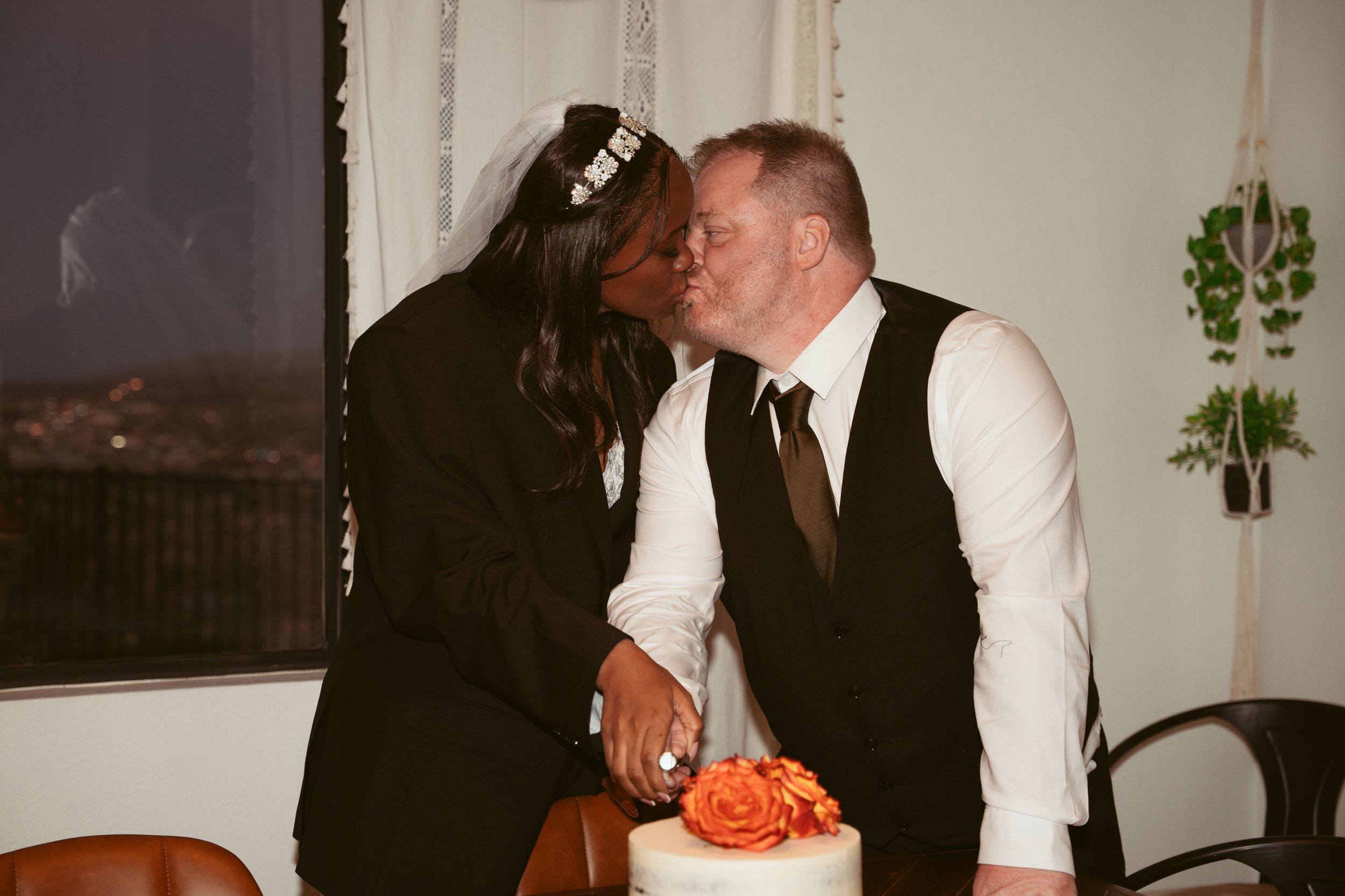 Intimate moment shared between newlyweds beside their wedding cake.