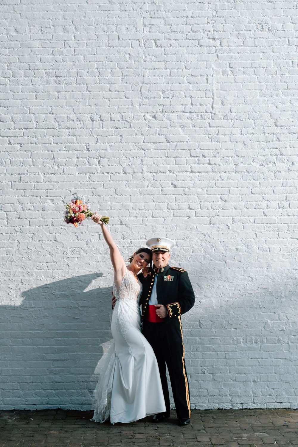Bride and groom holding hands with colorful florals in Pensacola street