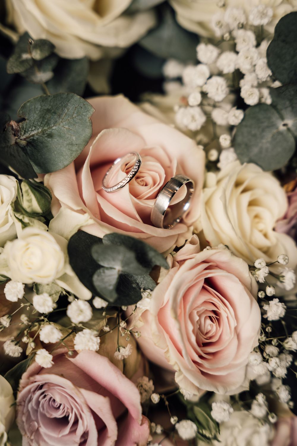 Elegant wedding bouquet featuring blush pink roses and white baby's breath with greenery.