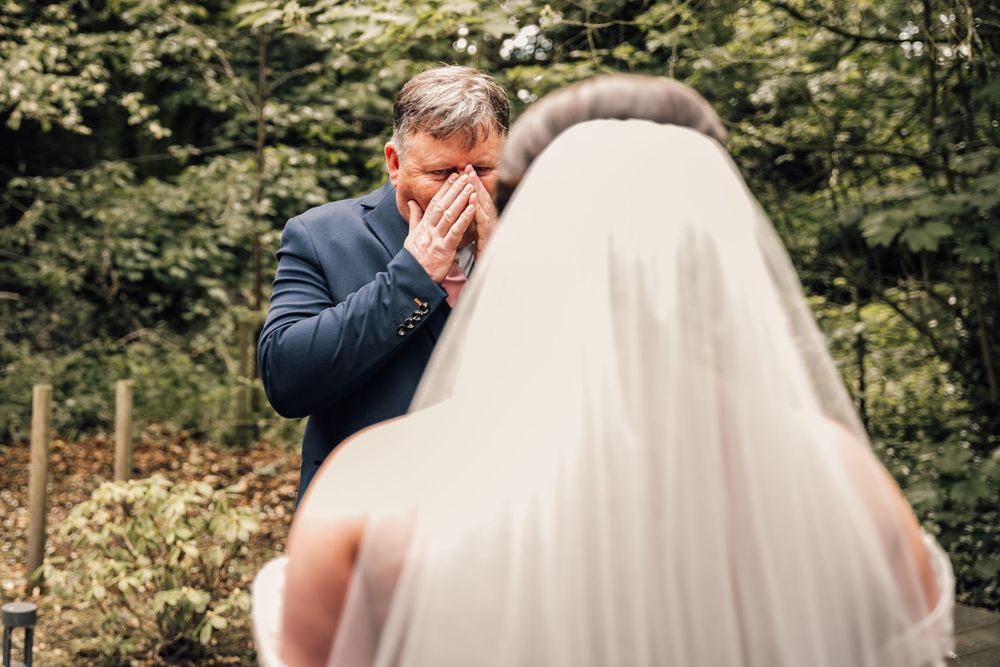 A joyful wedding ceremony moment captured outdoors with greenery in the background.