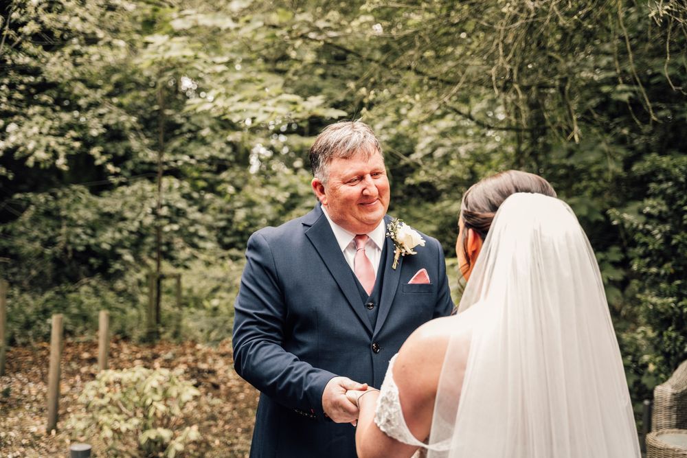 Emotional outdoor wedding ceremony moment surrounded by lush green trees.